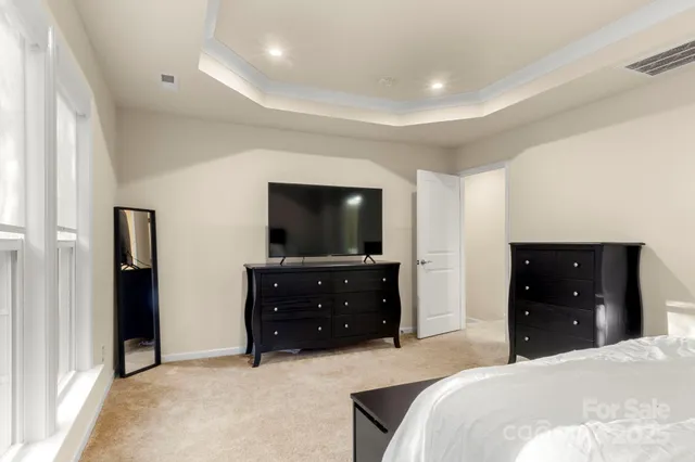 a bedroom with a bed and a flat tv screen on dresser