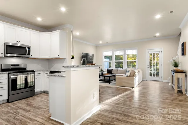 a living room with stainless steel appliances furniture and a wooden floor