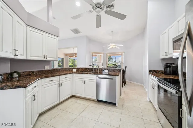 a kitchen with stainless steel appliances granite countertop a refrigerator a stove a sink and white cabinets