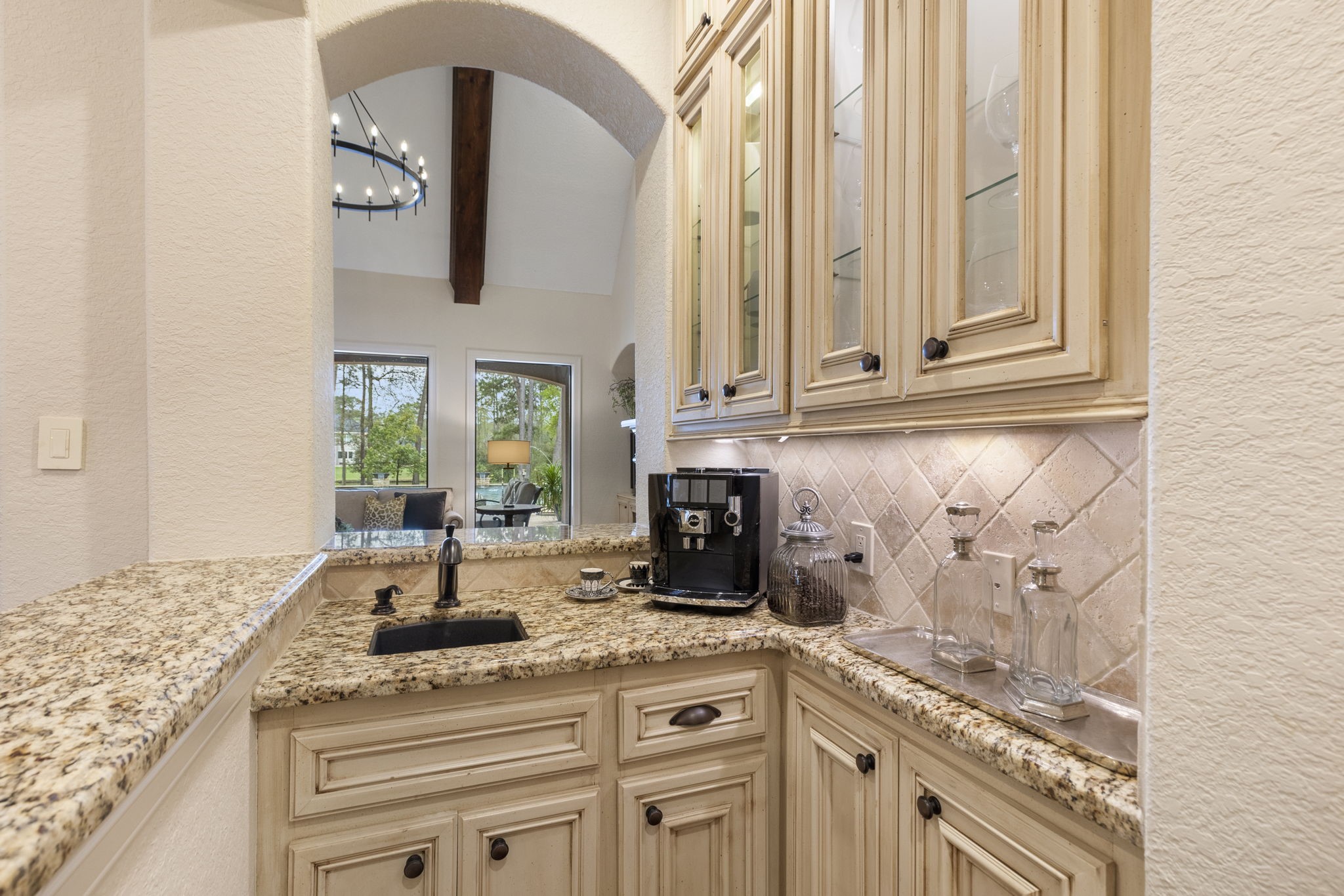 28227 KAILEES Court Spring, TX 77386 - Photo 16 of 48 Dedicated coffee and wine serving bar with charming arched openings, bar sink, granite countertops, glass-front cabinetry with accent lighting, and under-cabinet illumination—perfect for entertaining or morning coffee rituals.