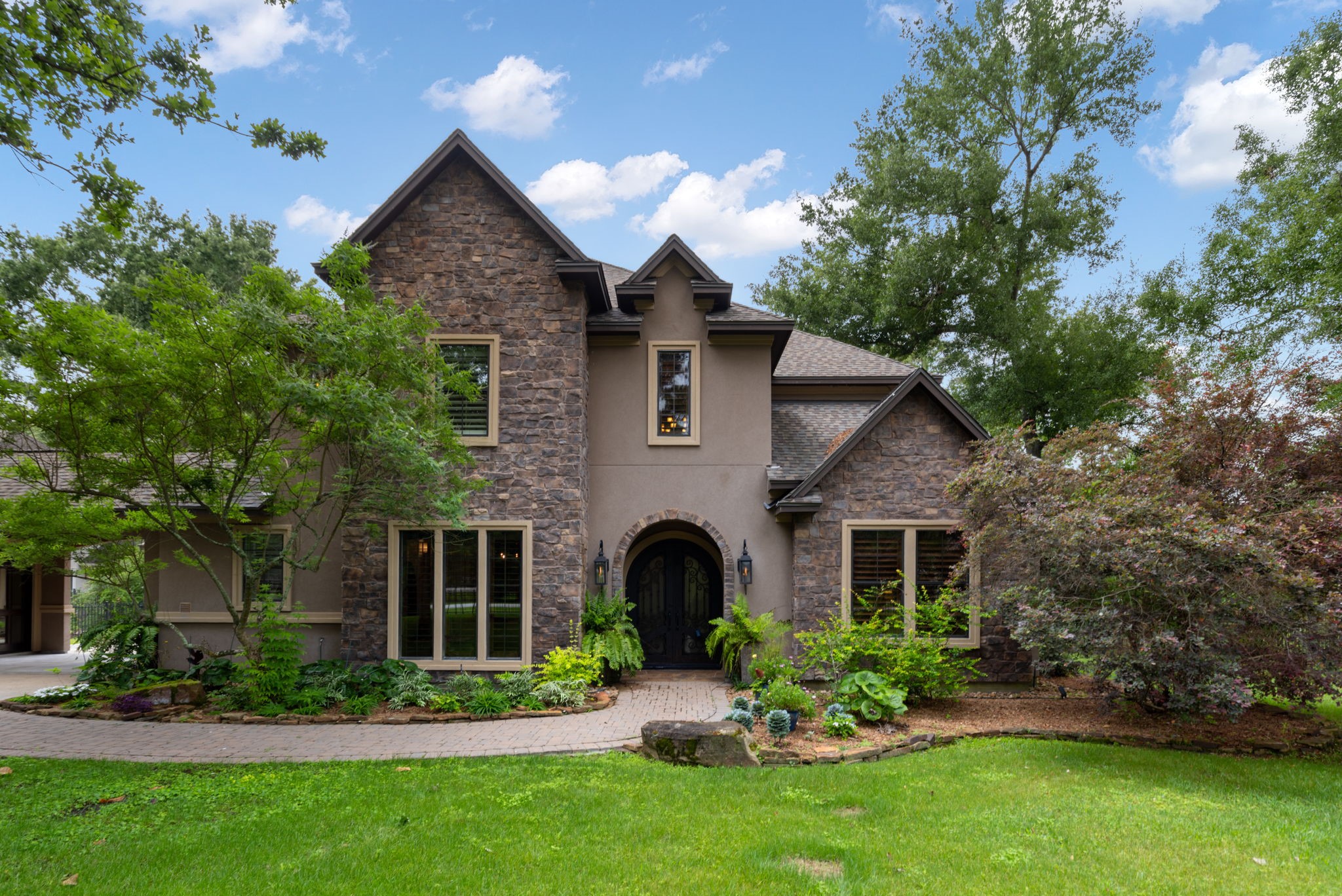 28227 KAILEES Court Spring, TX 77386 - Photo 2 of 48 Striking stone and stucco custom home with exceptional curb appeal, highlighted by professional landscaping, stone-lined garden beds, a paver-lined driveway, guest parking, and an porte-cochère.