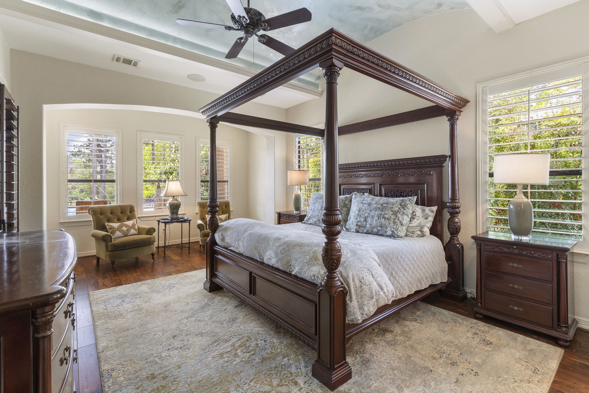 28227 KAILEES Court Spring, TX 77386 - Photo 21 of 48 Spacious downstairs Primary Suite with rich wood flooring and an elegant barrel ceiling with crown molding and accent lighting. Features a sitting area, wall of windows overlooking the pool and lake, sound system, ceiling fan, and private patio access.