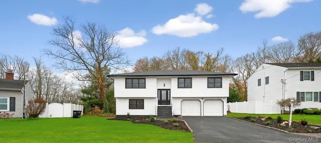 a view of a white house with a yard and table and chairs under an umbrella