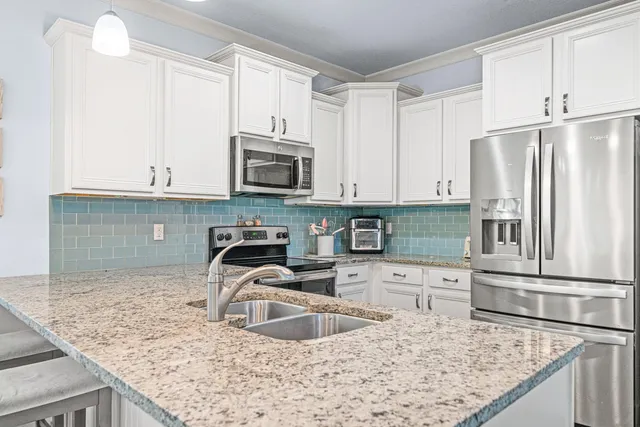 a kitchen with granite countertop a sink a stove and refrigerator