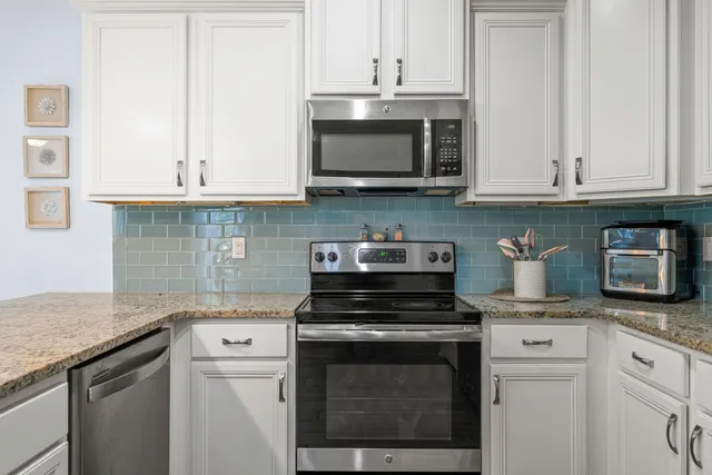 a kitchen with granite countertop white cabinets and stainless steel appliances