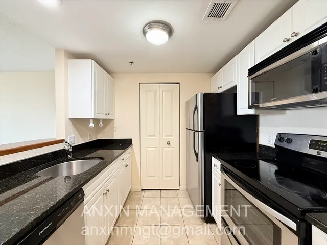 a kitchen with granite countertop a refrigerator and a sink