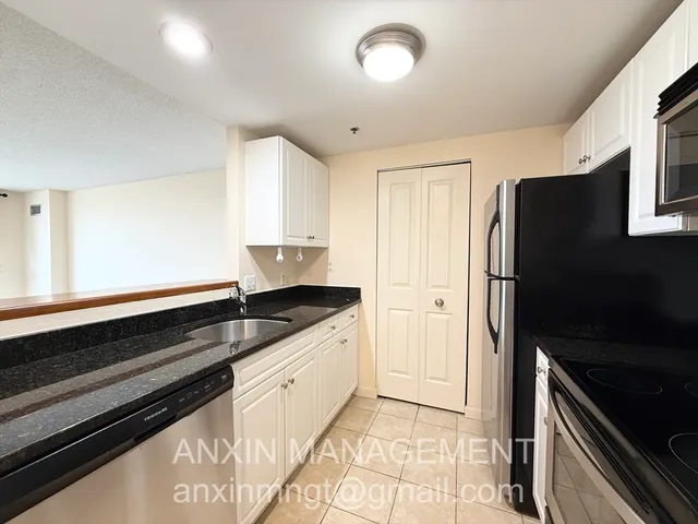 a kitchen with granite countertop a refrigerator and a sink