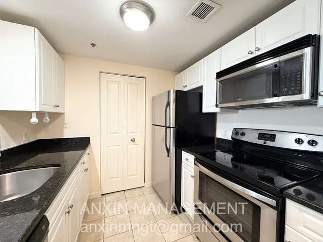 a kitchen with stainless steel appliances granite countertop a refrigerator and a stove