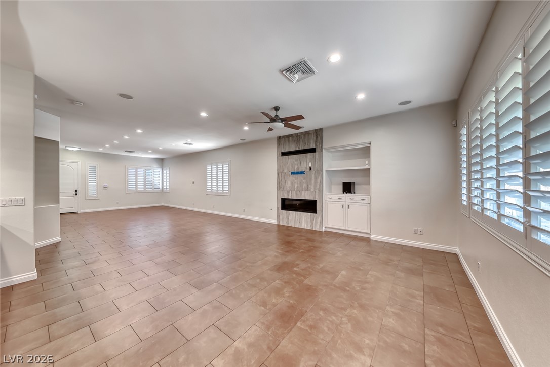2122 Mooreview Street Henderson, NV 89012 - Photo 14 of 44 A spacious living area with ceramic tile flooring, a fireplace, and built-in shelving offers comfort and warmth.