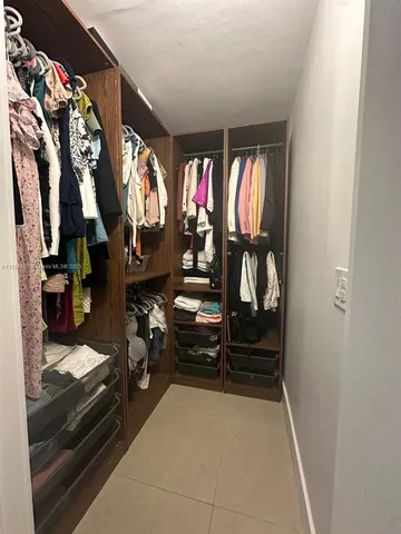a view of walk in closet with clothes and shoes
