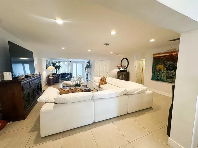 a living room with furniture a flat screen tv and a refrigerator