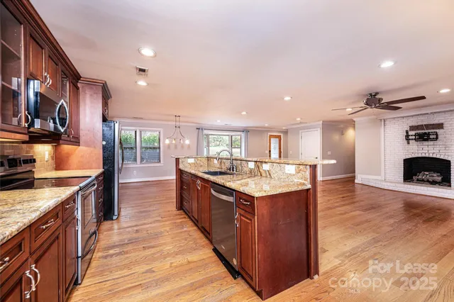a kitchen with stainless steel appliances granite countertop a kitchen island a stove a sink and a refrigerator