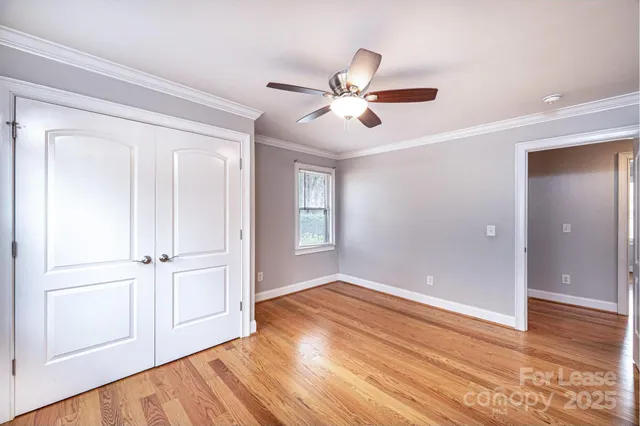 a view of empty room with wooden floor and fan