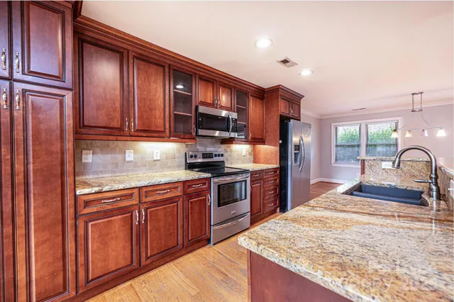 a kitchen with stainless steel appliances granite countertop wooden cabinets a stove top oven a sink and dishwasher