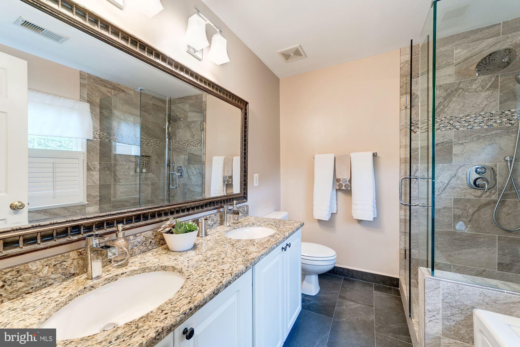 1283 Weatherstone Court Reston, VA 20194 - Photo 21 of 38 a bathroom with a granite countertop sink a toilet a mirror and shower