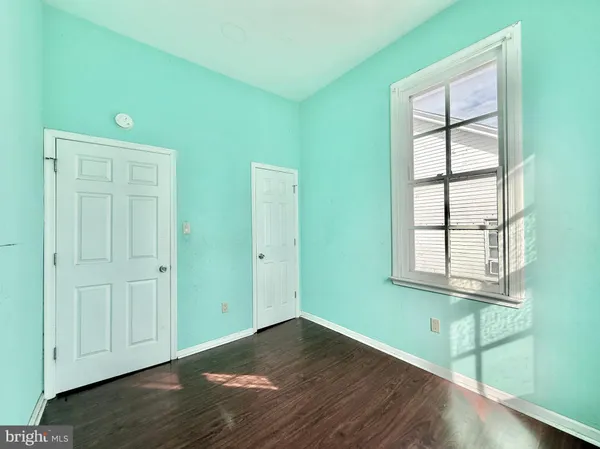 an empty room with wooden floor chandelier fan and windows
