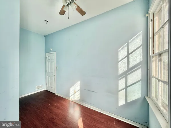 an empty room with wooden floor ceiling fan and windows