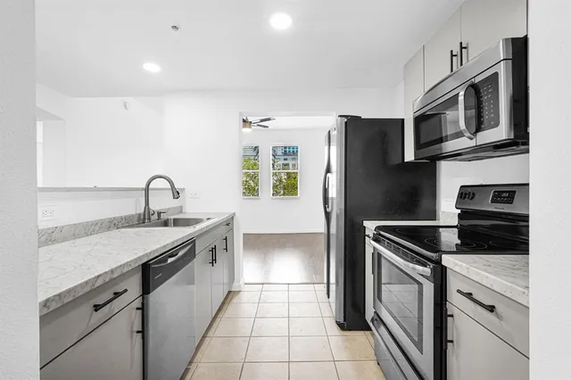 a kitchen with stainless steel appliances granite countertop a sink and a refrigerator