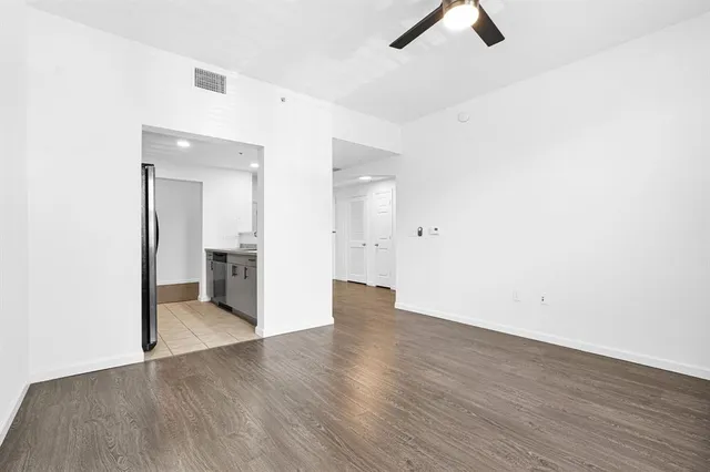 a view of empty room with wooden floor and fan