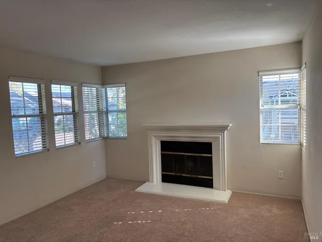 an empty room with windows and fireplace
