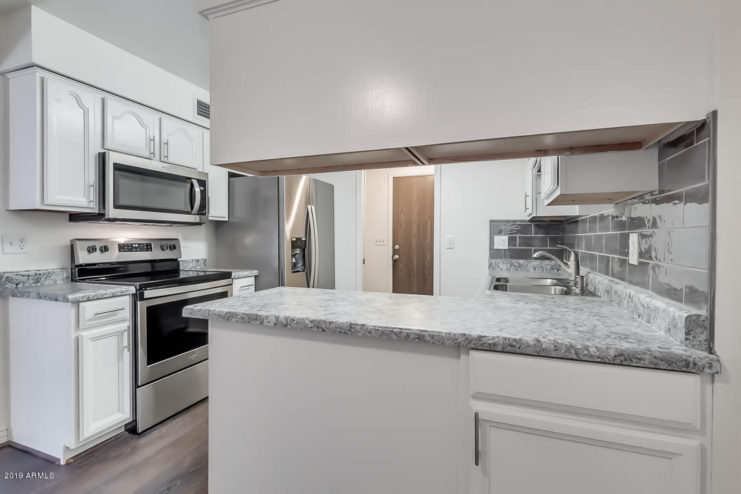 1860 East Inverness Avenue Mesa, AZ 85204 - Photo 12 of 29 a kitchen with stainless steel appliances granite countertop a sink stove microwave and refrigerator