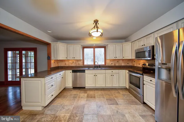 a kitchen with granite countertop a sink stainless steel appliances and cabinets