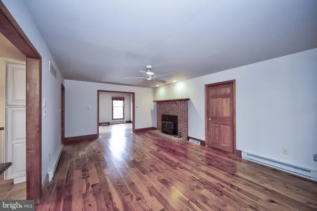 an empty room with wooden floor fireplace and windows