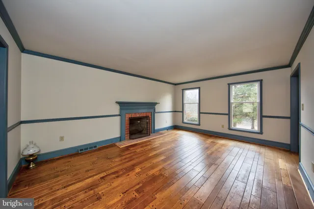 a view of empty room with wooden floor and fireplace
