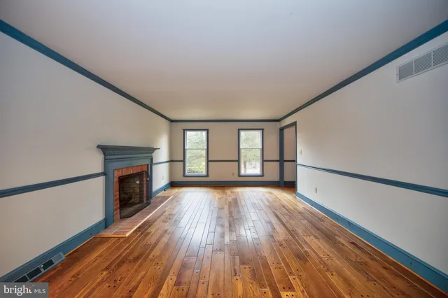 a view of empty room with wooden floor and fireplace