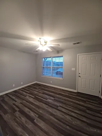 a view of an empty room with wooden floor and a window