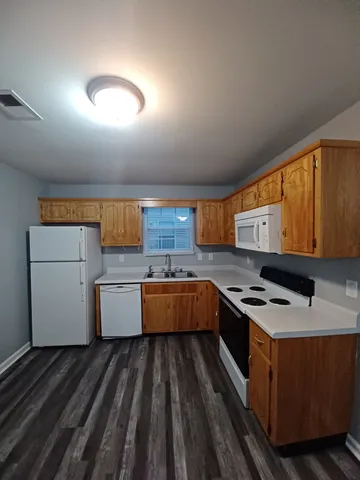 a kitchen with a stove wooden floors and a sink
