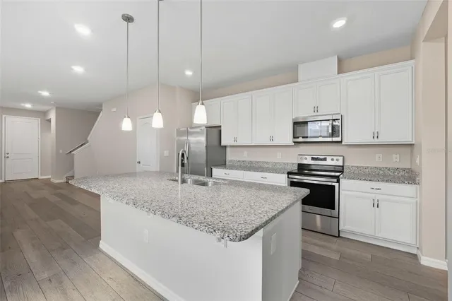 a kitchen with stainless steel appliances granite countertop a sink a stove a oven a kitchen island with cabinets and wooden floor