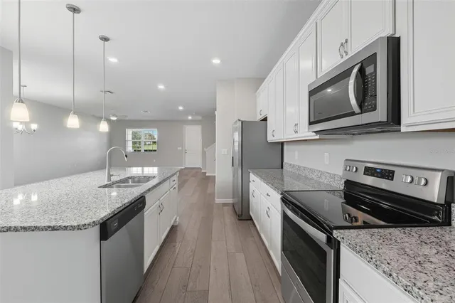 a kitchen with stainless steel appliances granite countertop a sink a stove and a microwave