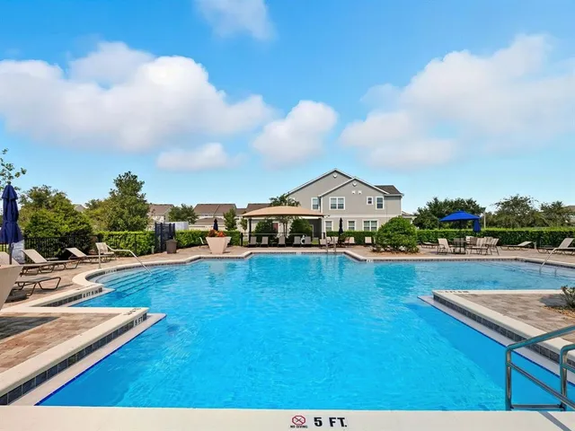 a view of swimming pool with outdoor seating and trees in the background