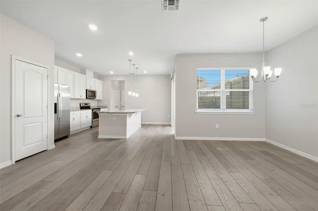 a view of a kitchen with center island wooden floor stainless steel appliances and windows
