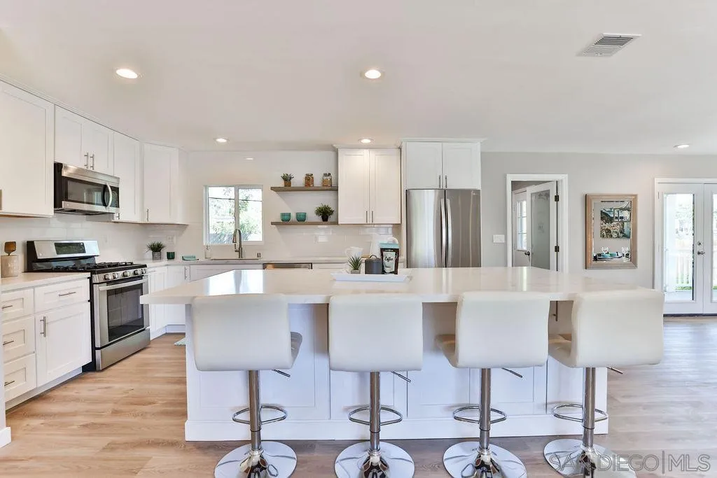 9802 Sierra Madre Road Spring Valley, CA 91977 - Photo 14 of 48 a kitchen with stainless steel appliances kitchen island granite countertop a dining table chairs refrigerator and sink