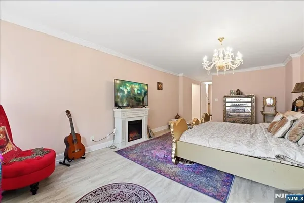 a bedroom with a bed potted plant on dresser and a chandelier