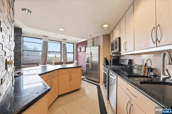 a large kitchen with granite countertop a large window and stainless steel appliances