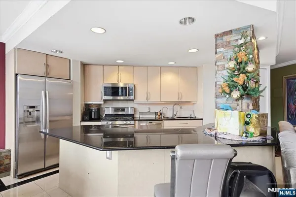 a kitchen with stainless steel appliances granite countertop a sink a stove a refrigerator a counter space and cabinets