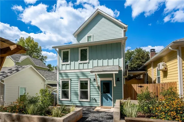 a view of a white house with large windows and a small yard