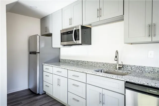 a kitchen with granite countertop white cabinets and stainless steel appliances