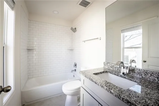 a bath room with a granite countertop toilet a sink and a bathtub