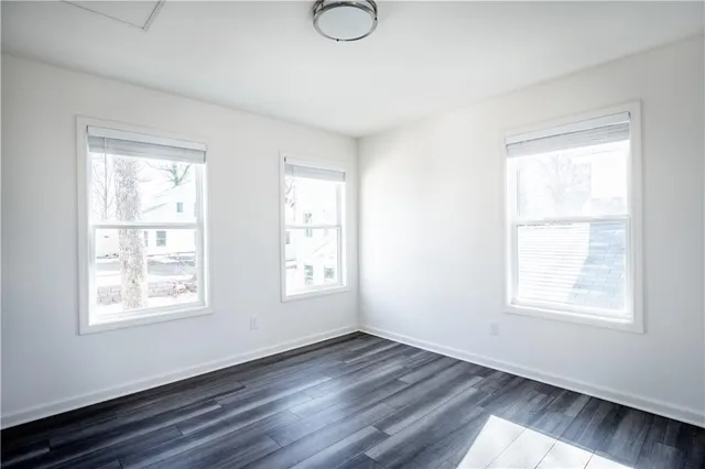 a view of an empty room with wooden floor and window