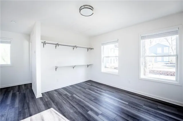 an empty room with wooden floor cabinet and windows
