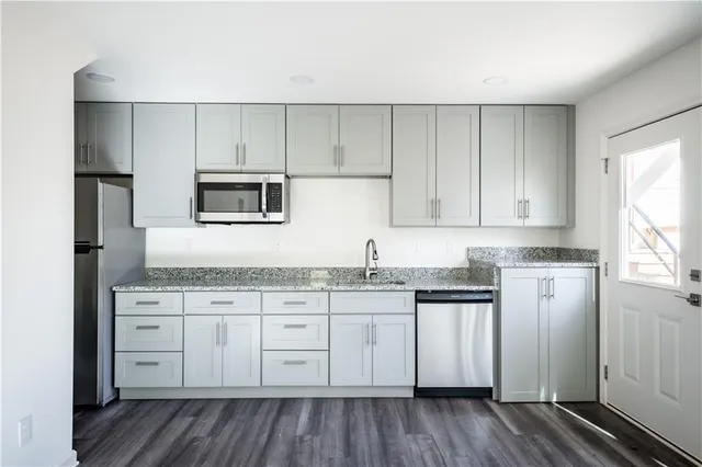 a kitchen with granite countertop white cabinets and stainless steel appliances