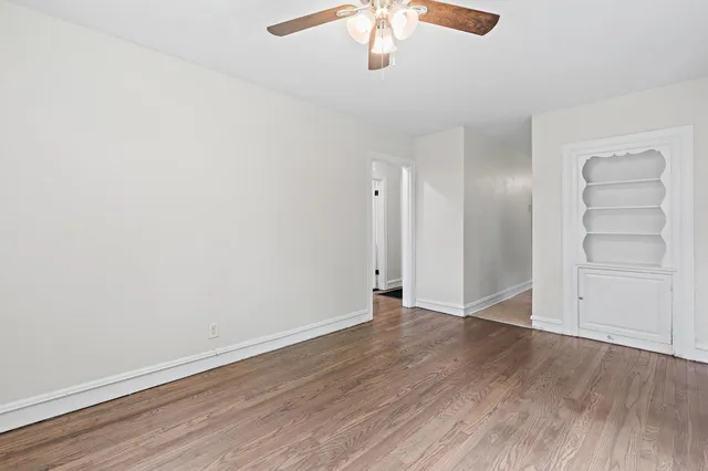 an empty room with wooden floor closet and windows