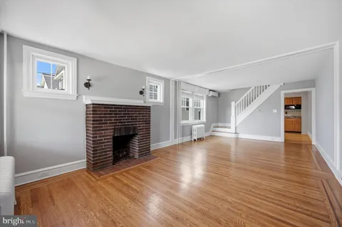 a view of an empty room with wooden floor fireplace and a window
