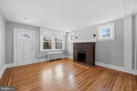 an empty room with wooden floor fireplace and windows