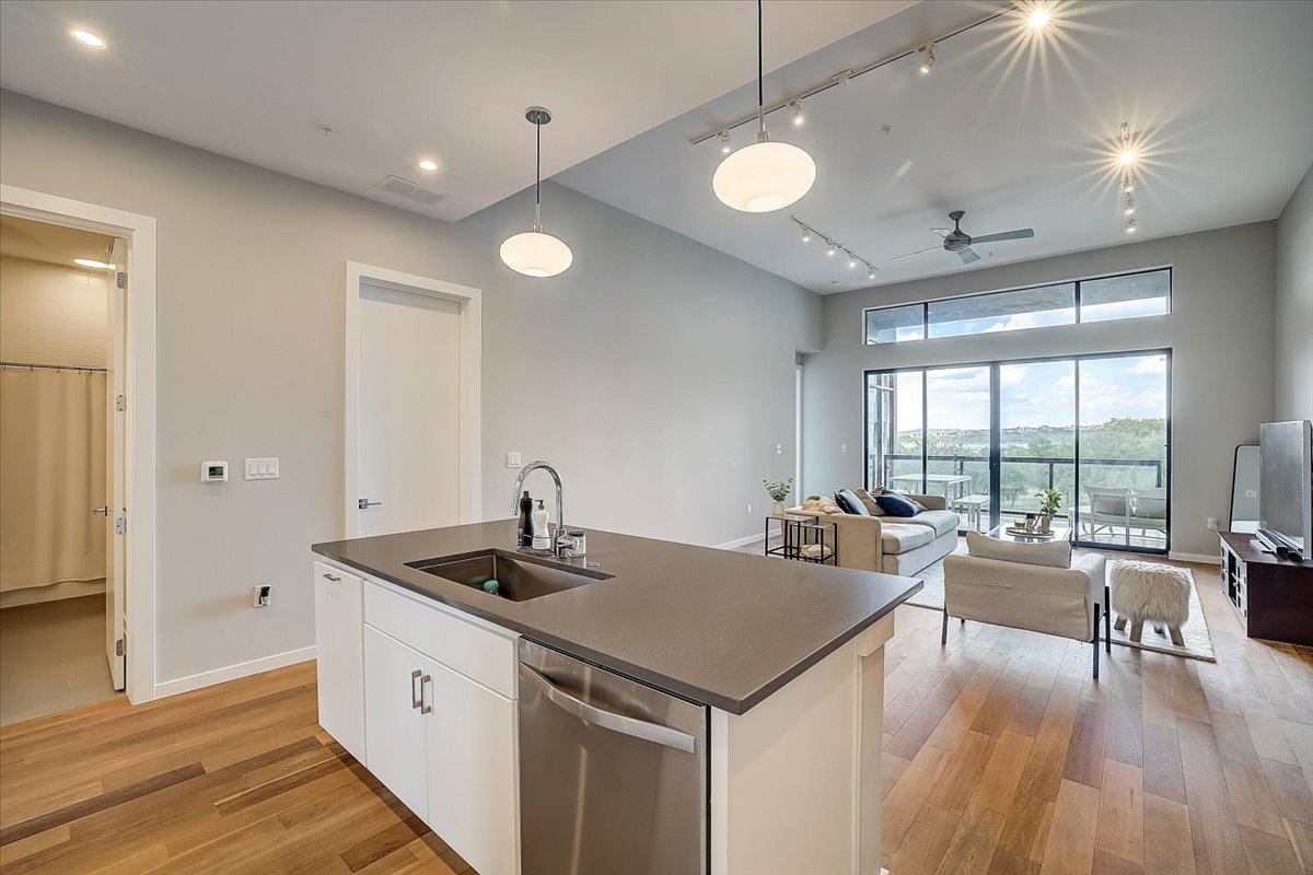 5921 Hiline Road, Unit 1204 Austin, TX 78734 - Photo 36 of 36 Kitchen with white cabinets, decorative light fixtures, dishwasher, open floor plan, and rail lighting