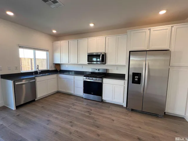 a kitchen with granite countertop a refrigerator and a stove top oven